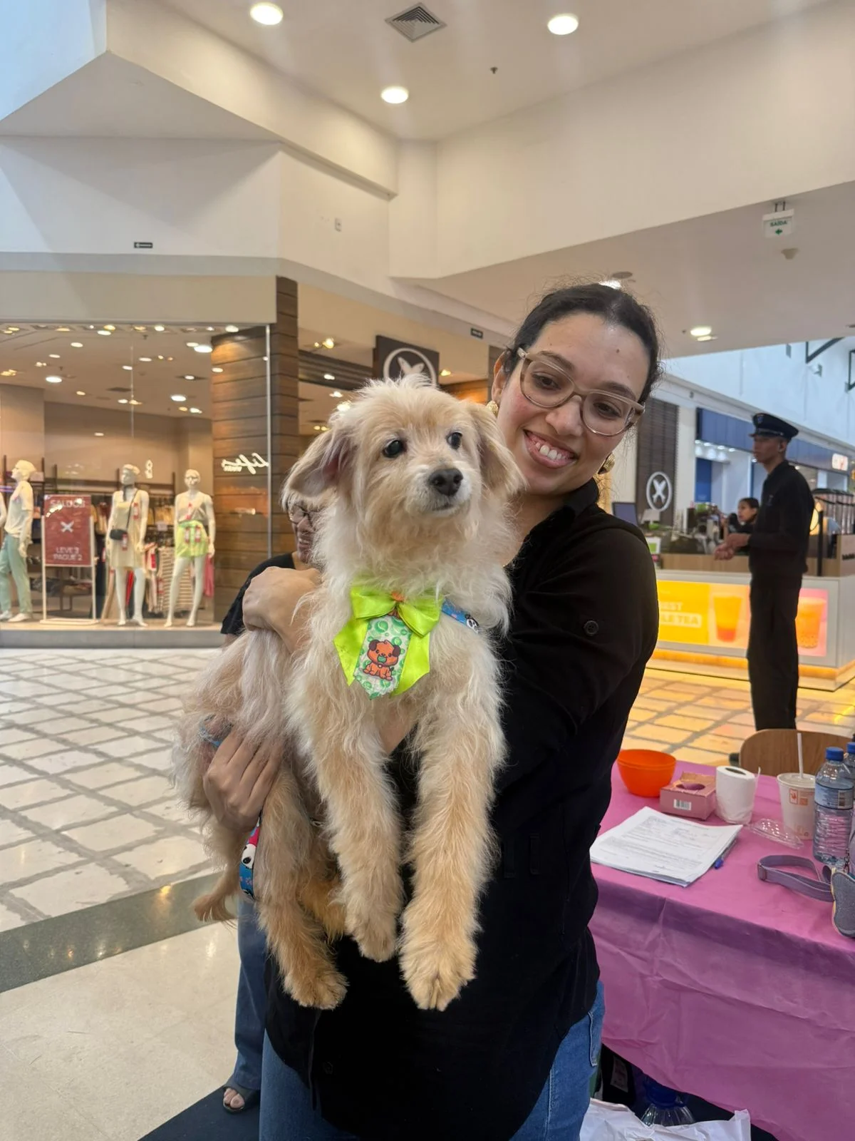 Foto da Daniela segurando seu cachorro adotado no shopping